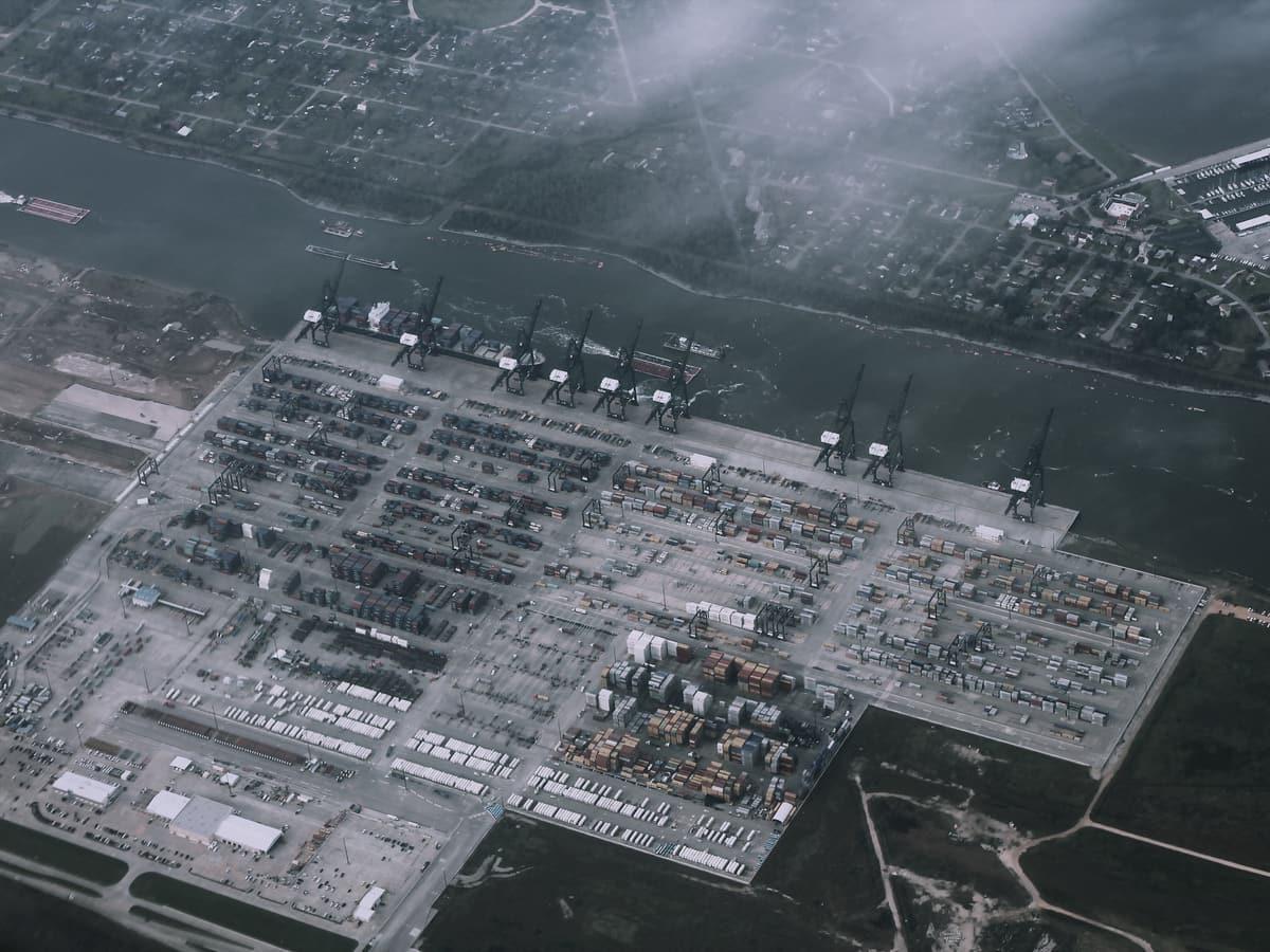 Aerial view of a bulk terminal, cranes and yard laid out along a river.